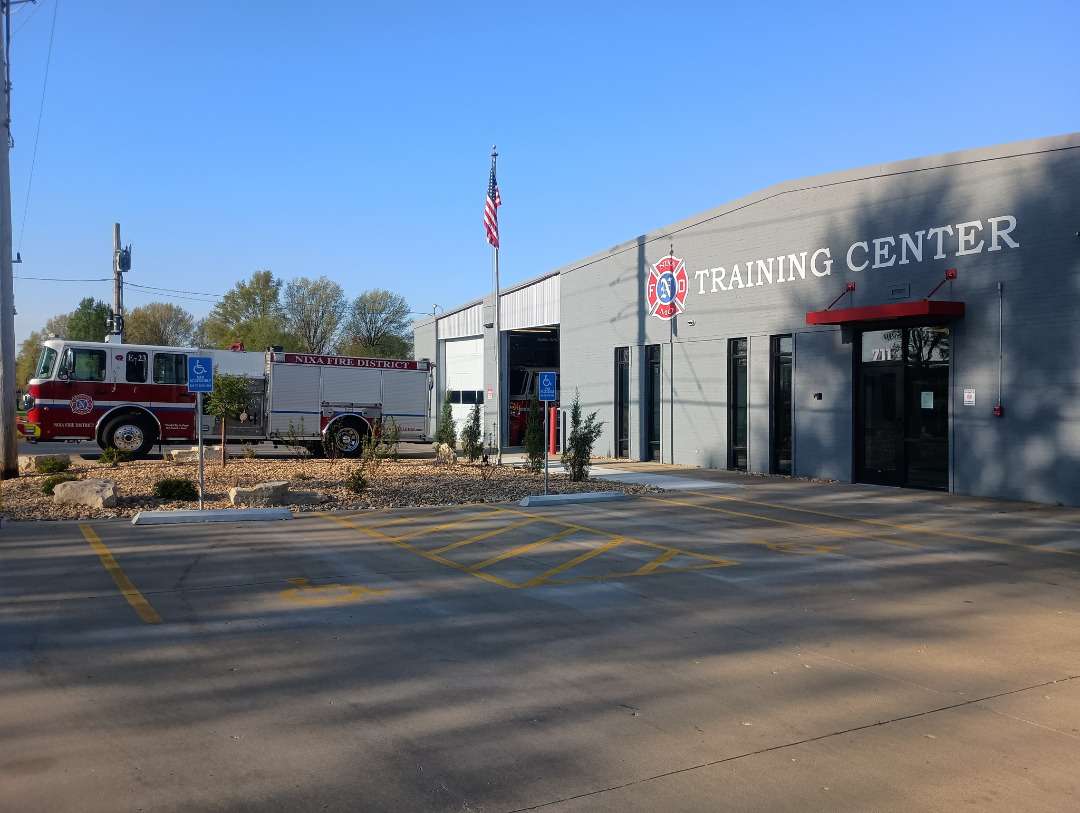 Exterior view of a fire engine parked outside of a large warehouse building with the words Training Center in large letters across the front